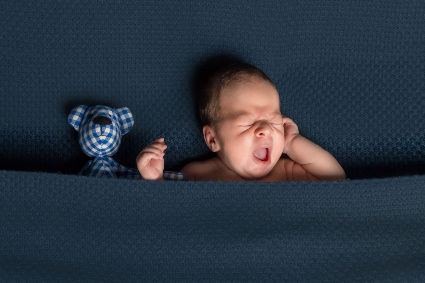 beba i plišani meda leže pokriveni plavim pokrivačem